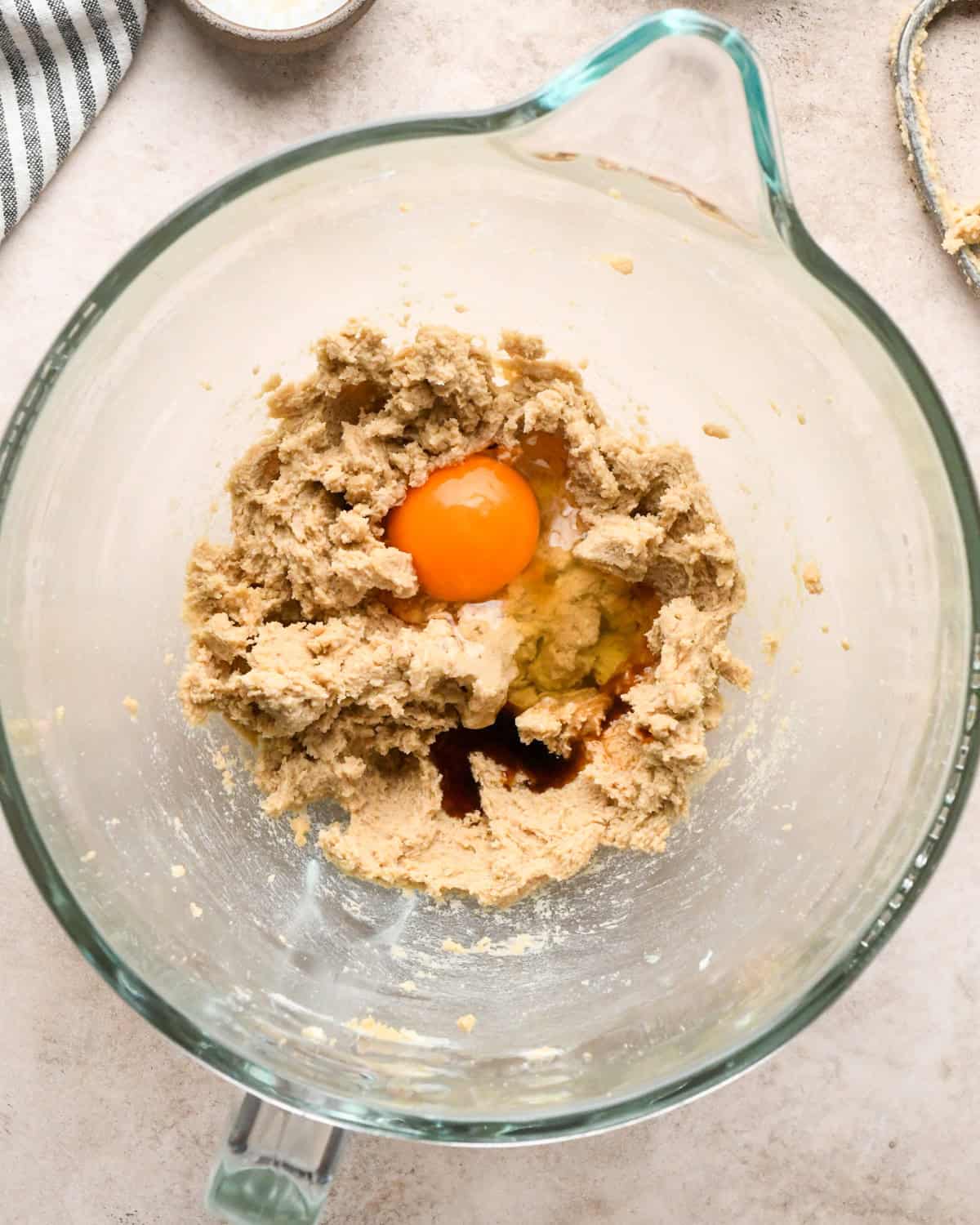 Making kitchen sink cookies - overhead photo of butter, sugar, brown sugar, egg, and vanilla being added to a clear measuring bowl.