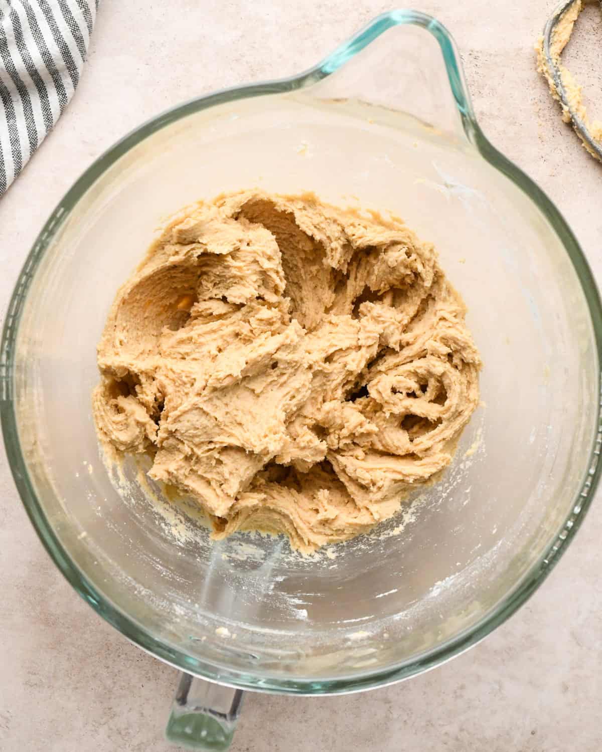 Making kitchen sink cookies - overhead photo of wet and dry ingredients being combined in a clear measuring bowl and mixed together with a stand mixer attachment.