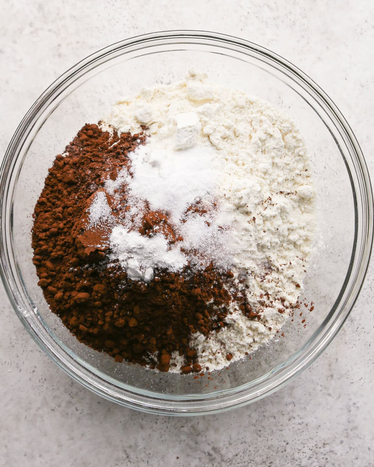 Making chocolate mint cookies - overhead photo of dry ingredients added to a clear mixing bowl.