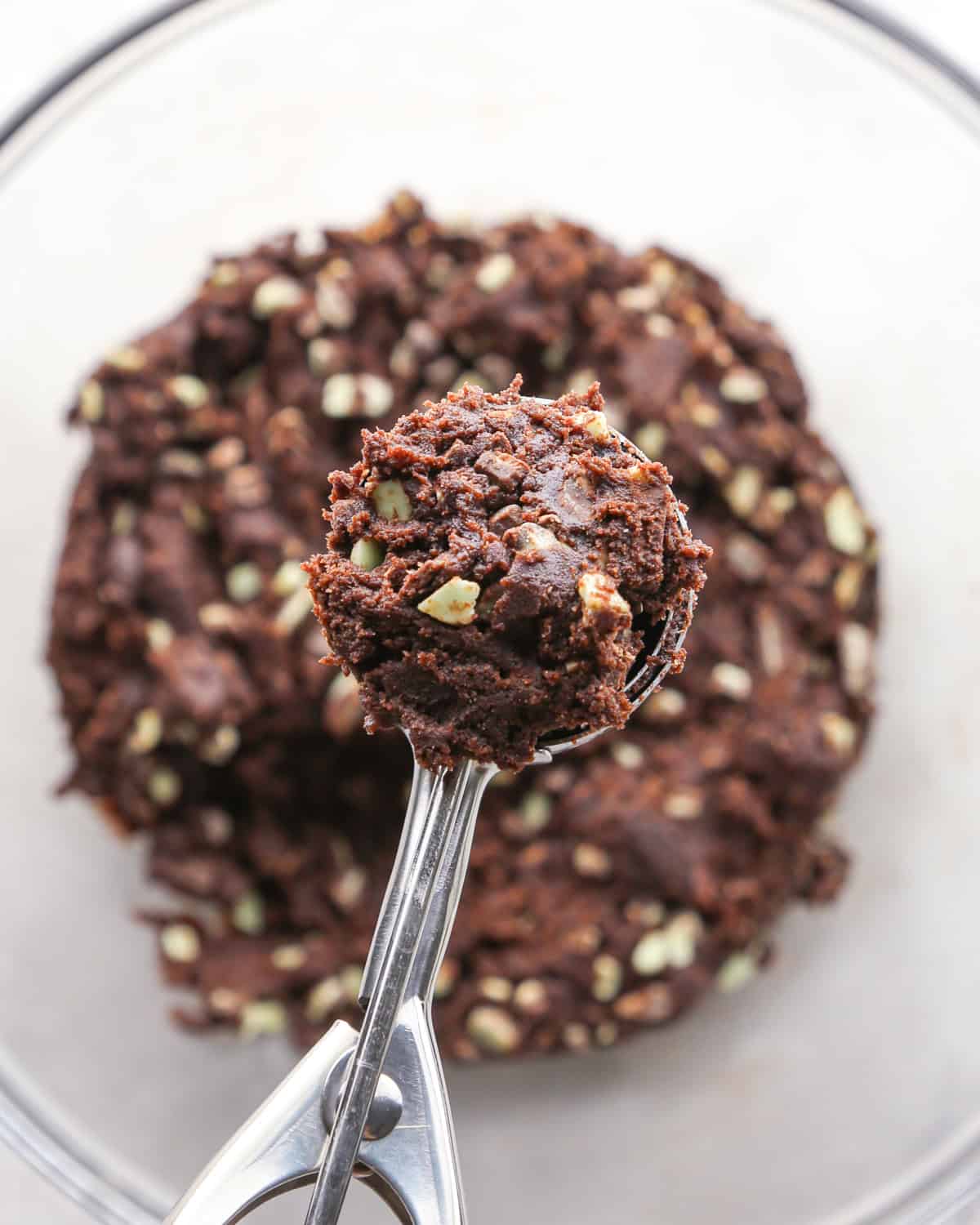 Making chocolate mint cookies - overhead photo of a cookie scoop scooping out chocolate mint cookie dough.