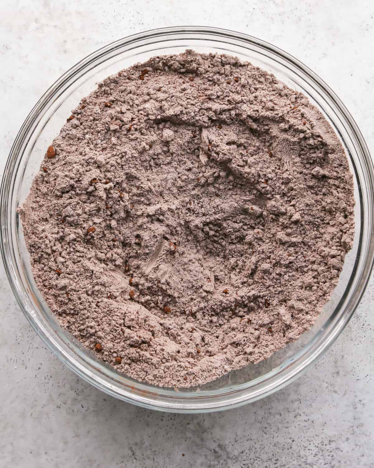 Making chocolate mint cookies - overhead photo of dry ingredients added to a clear mixing bowl and mixed together.