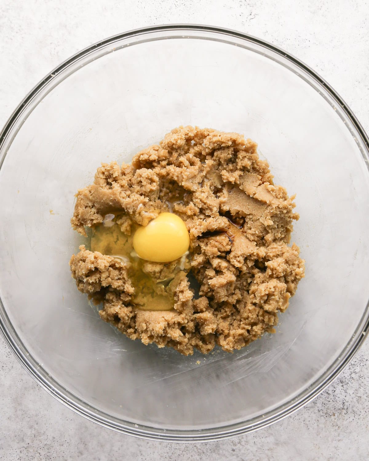 Making chocolate mint cookies - overhead photo of butter, sugar, brown sugar, and an egg in a clear mixing bowl.