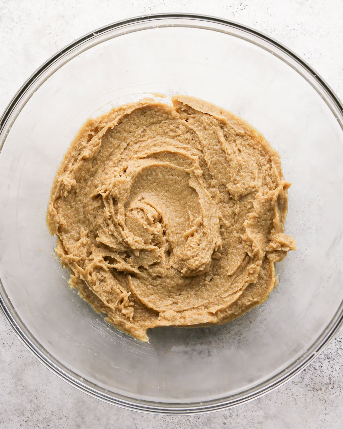 Making chocolate mint cookies - overhead photo of butter, sugar, brown sugar, and an egg in a clear mixing bowl and mixed together.