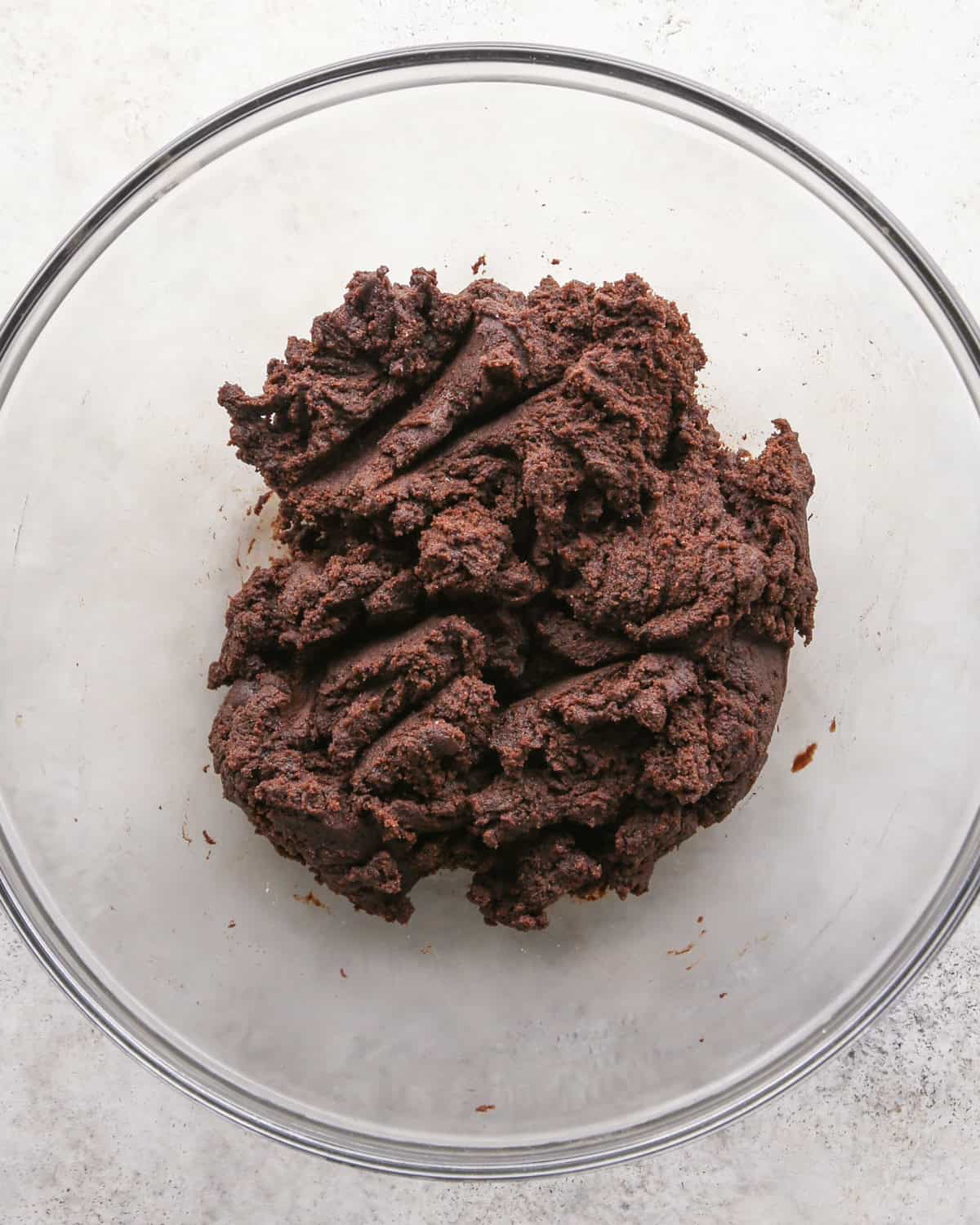 Making chocolate mint cookies - overhead photo of wet and dry ingredients mixed together in a clear mixing bowl.