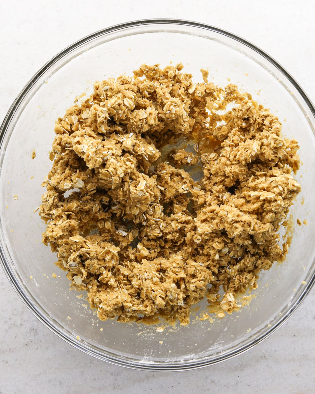 Making cranberry oatmeal cookies - overhead photo of old-fashioned oats being added to the cookie dough and mixed together.