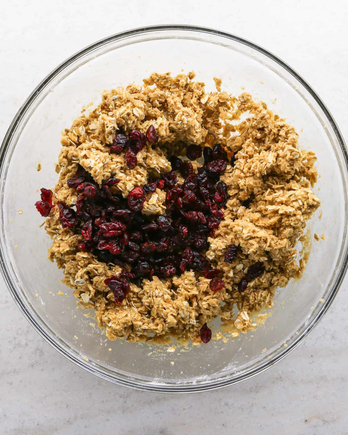 Making cranberry oatmeal cookies - overhead photo of dried cranberries being added to the cookie dough.