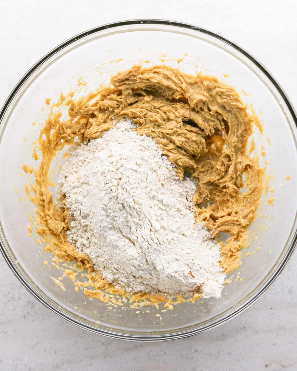 Making cranberry oatmeal cookies - overhead photo of wet and dry ingredients being combined in a clear mixing bowl.