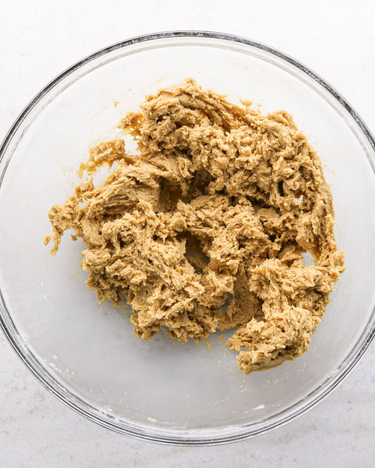 Making cranberry oatmeal cookies - overhead photo of wet and dry ingredients mixed together in a clear mixing bowl.