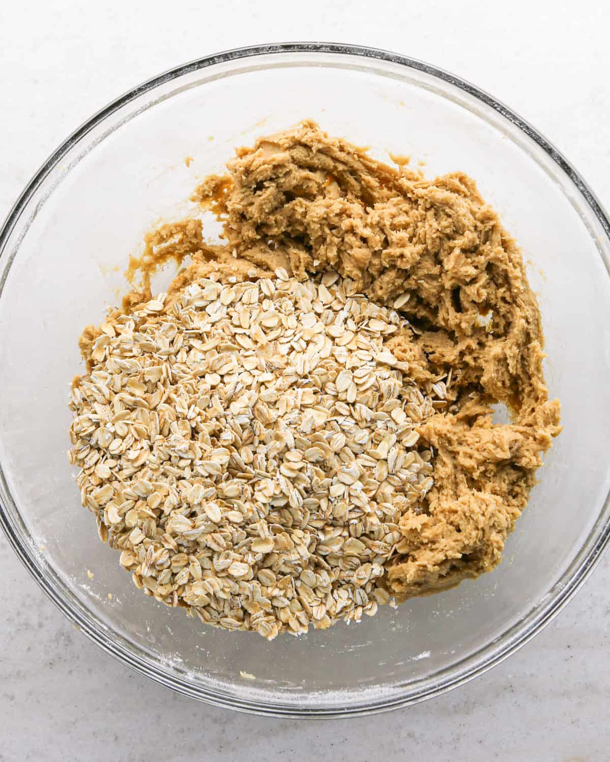 Making cranberry oatmeal cookies - overhead photo of old-fashioned oats being added to the cookie dough.