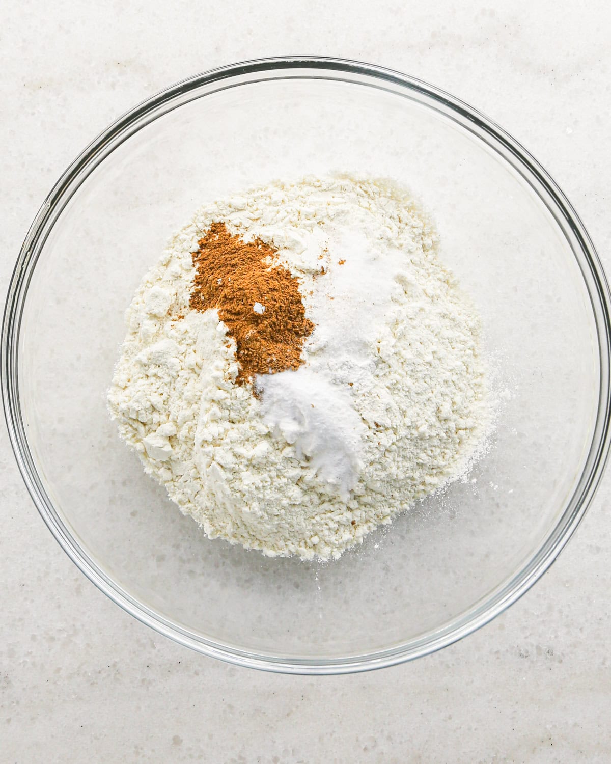 Making cranberry oatmeal cookies - overhead photo of dry ingredients in a clear mixing bowl.