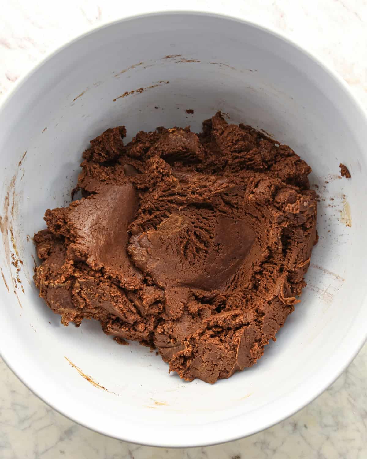 Making chocolate peanut butter chip cookies - dry ingredients and wet ingredients mixed together in a white bowl.
