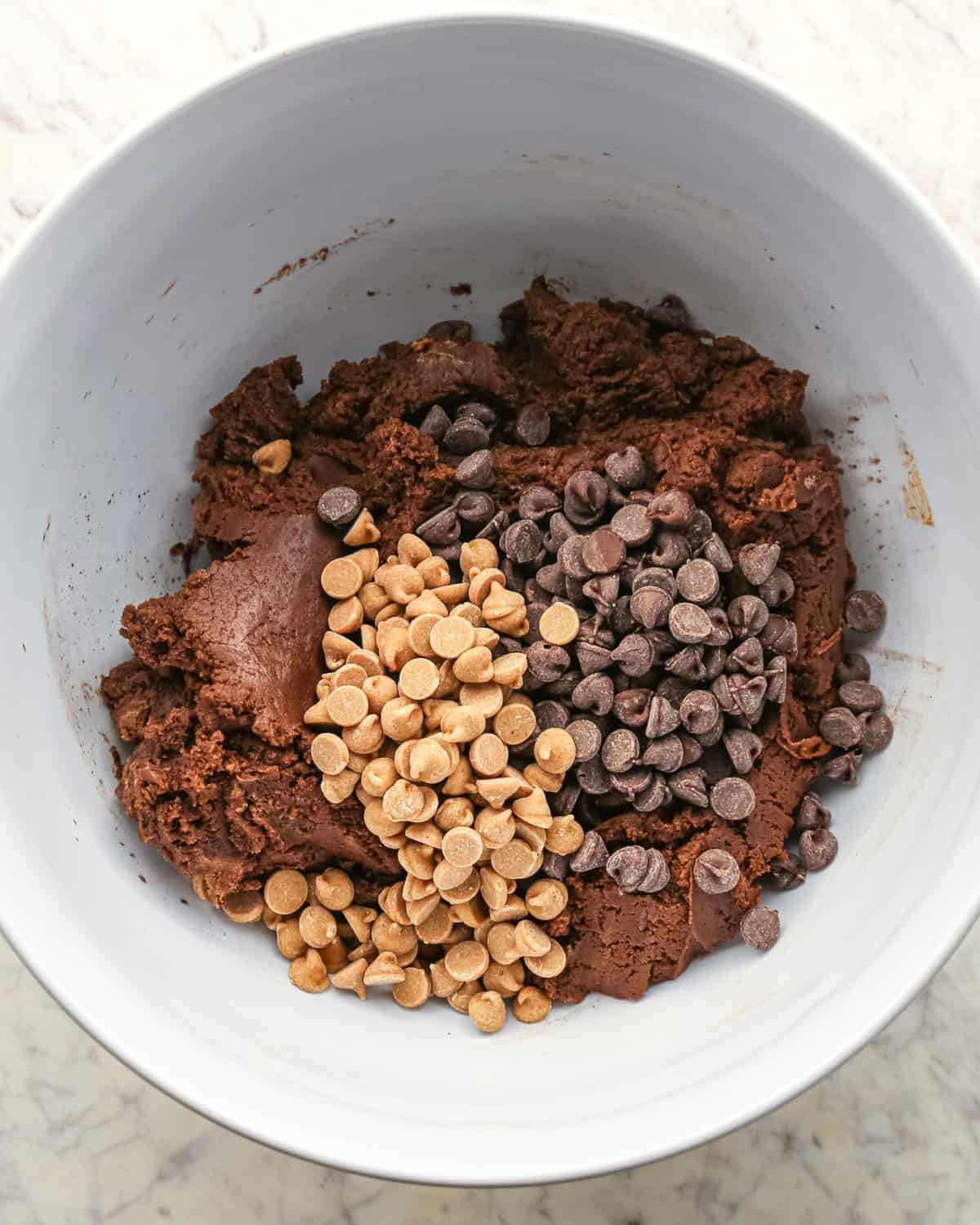 Making chocolate peanut butter chip cookies - chocolate chips and peanut butter chips added to cookie dough.