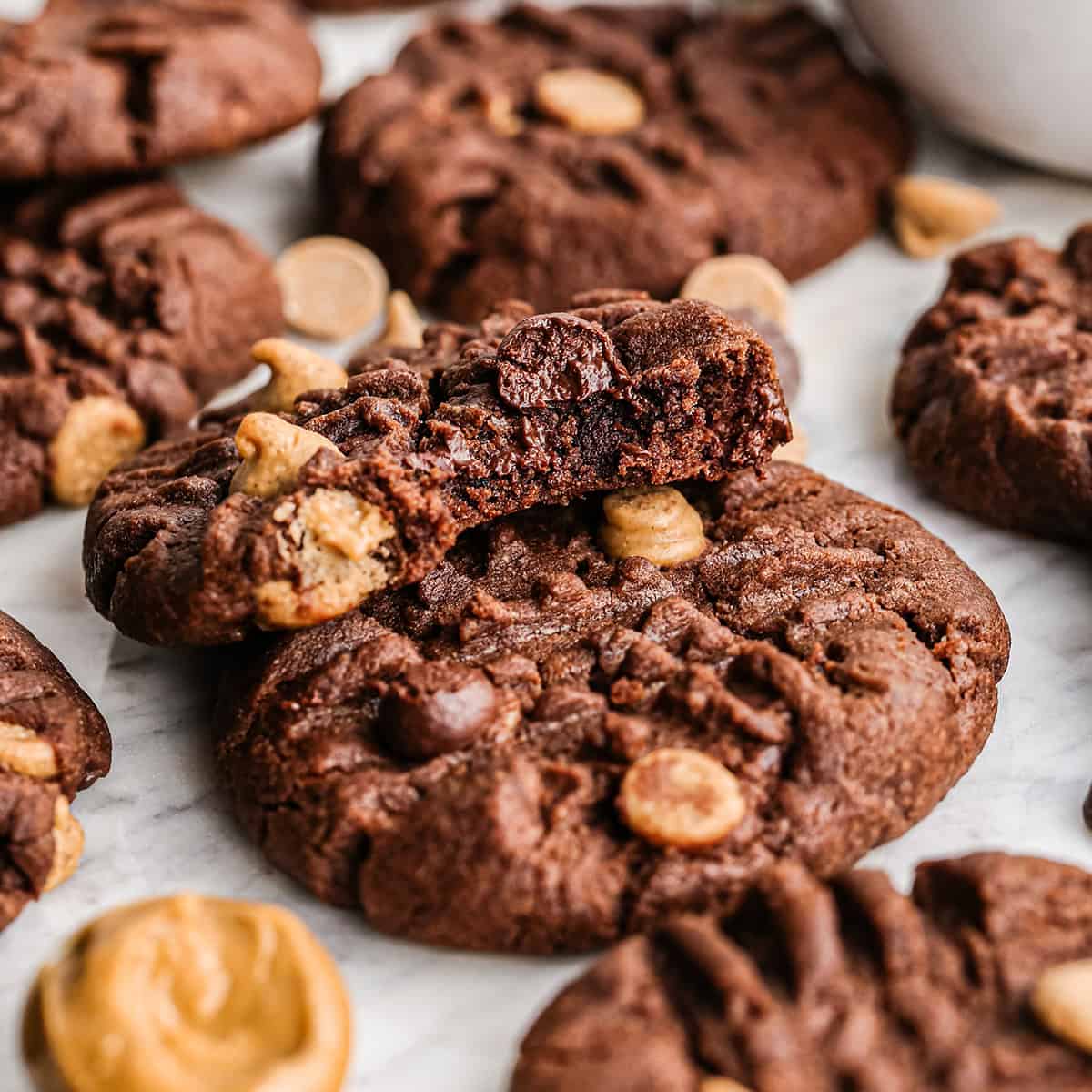 Close up photo of chocolate peanut butter chip cookies with one cookie partially eaten on top.