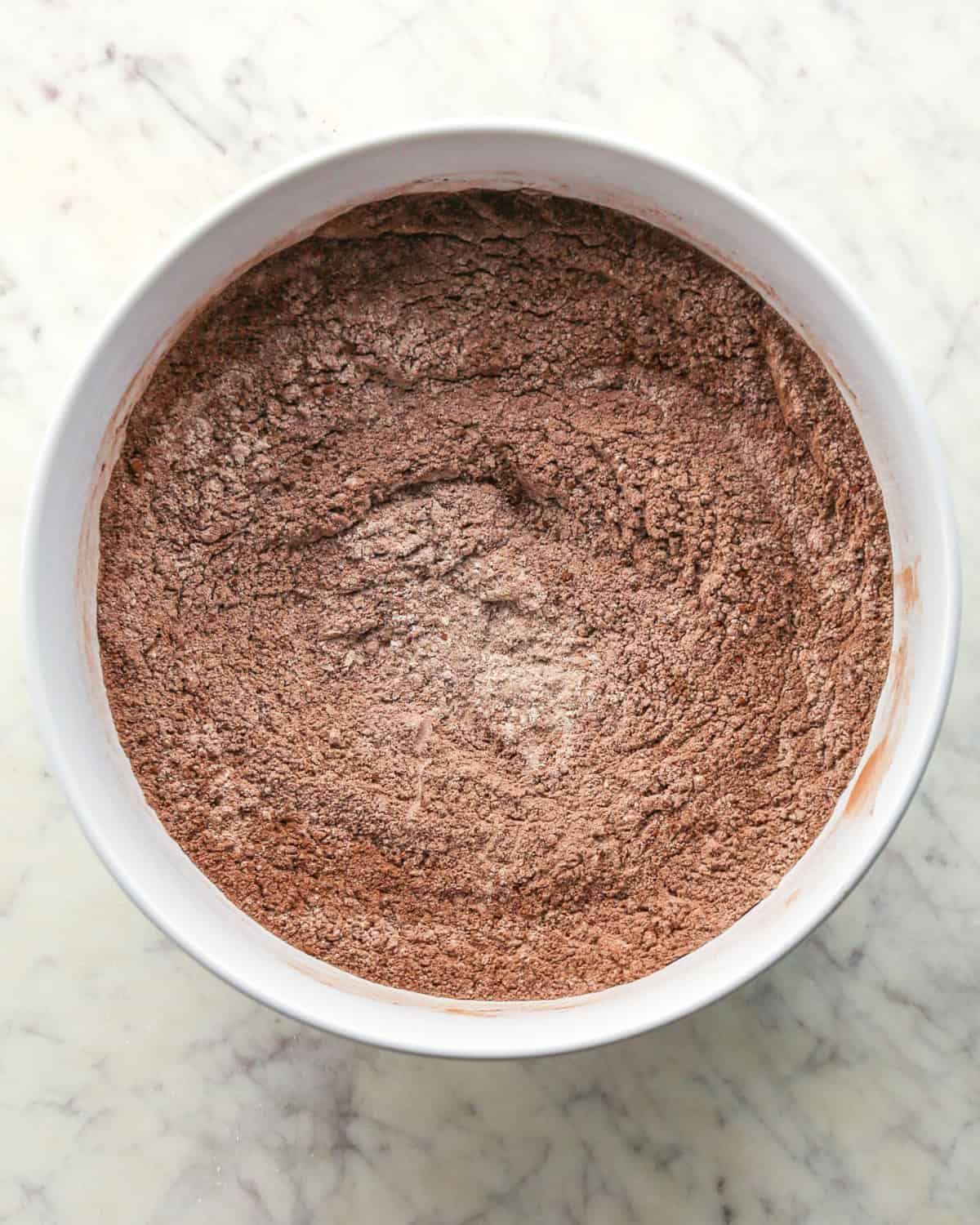 Making chocolate peanut butter chip cookies - dry ingredients placed in a white bowl and mixed together.