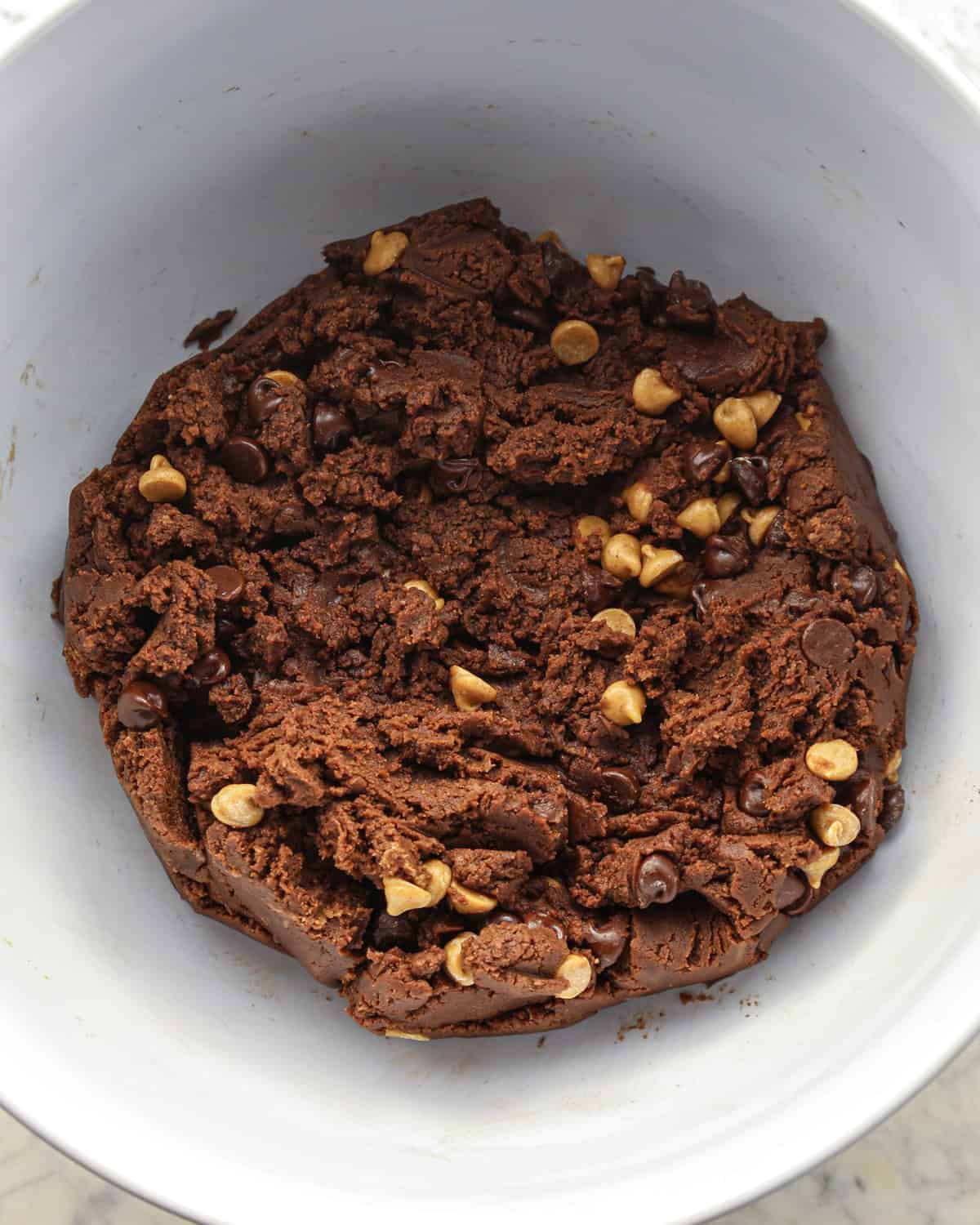 Making chocolate peanut butter chip cookies - chocolate chips and peanut butter chips added to cookie dough and mixed together.