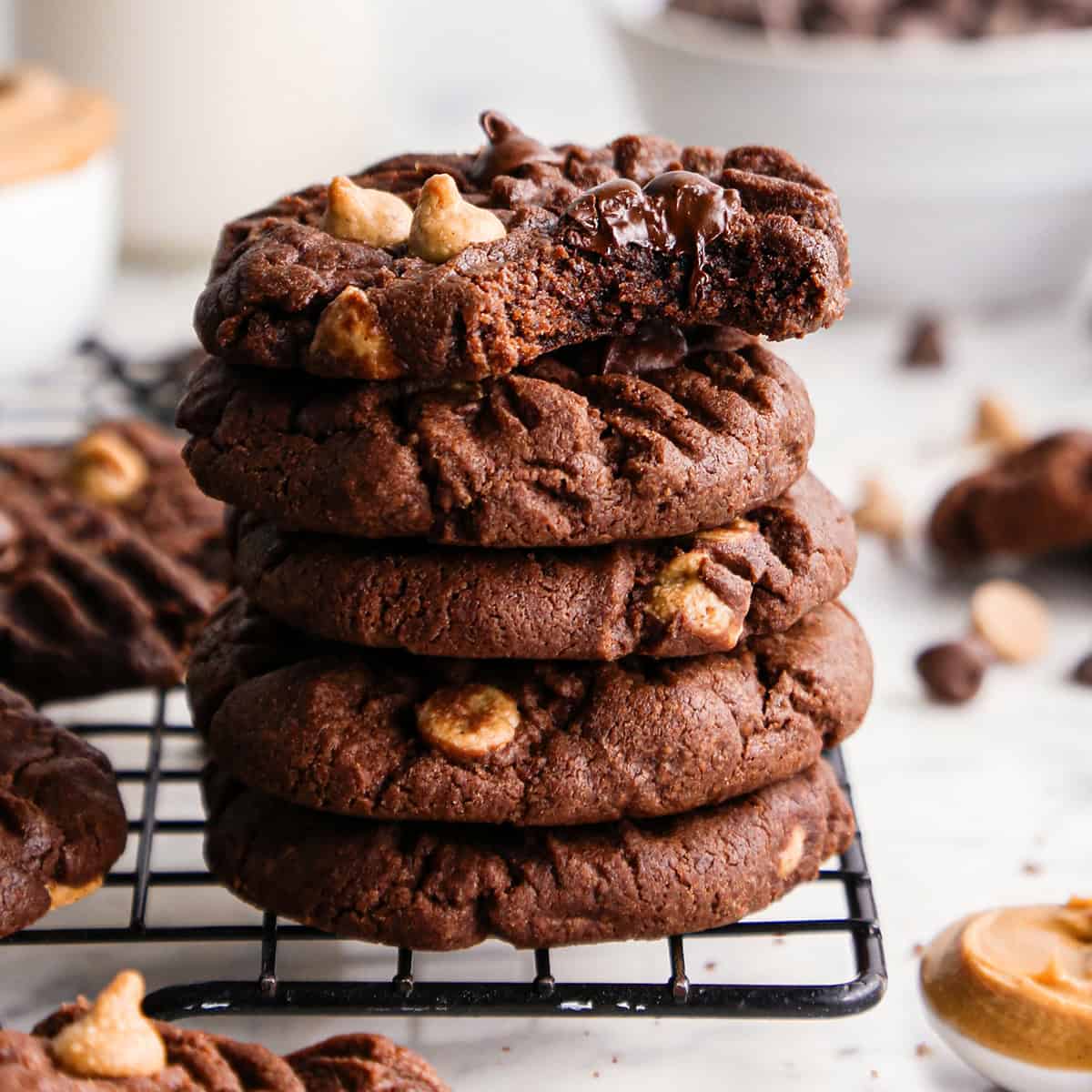 Stack of 5 chocolate peanut butter chip cookies with one cookie partially eaten on top.