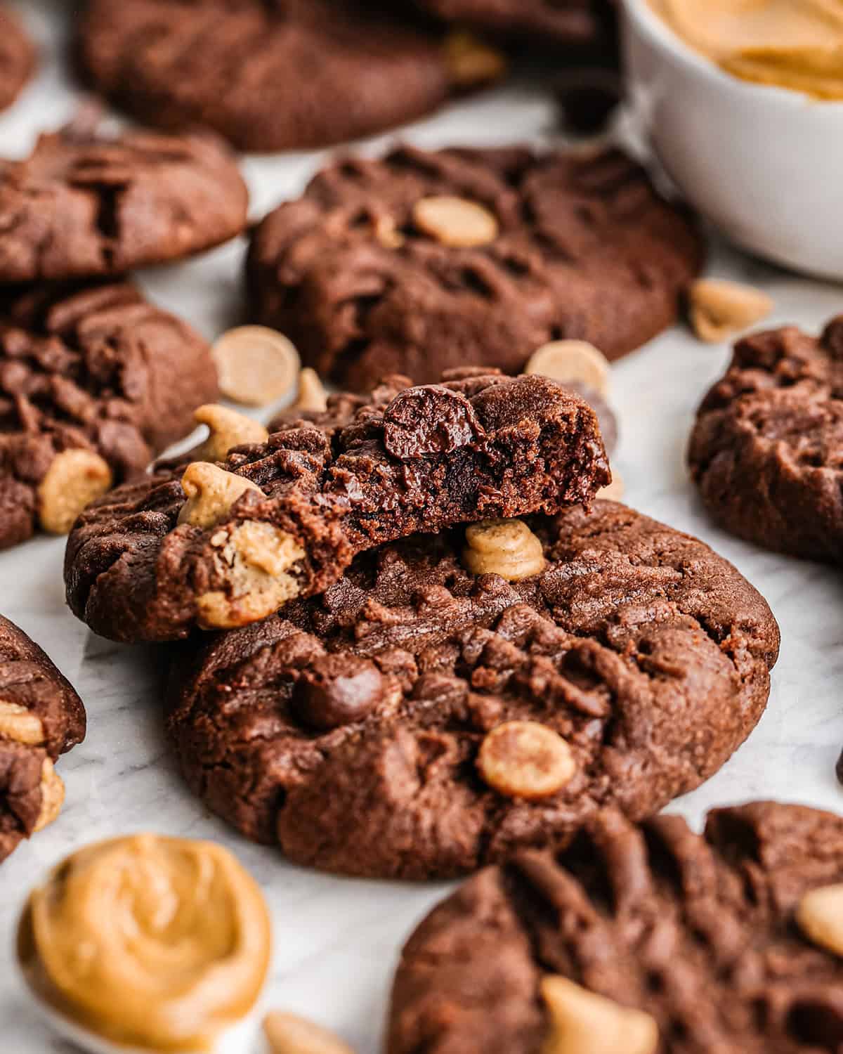 Close up photo of chocolate peanut butter chip cookies with one cookie partially eaten on top.