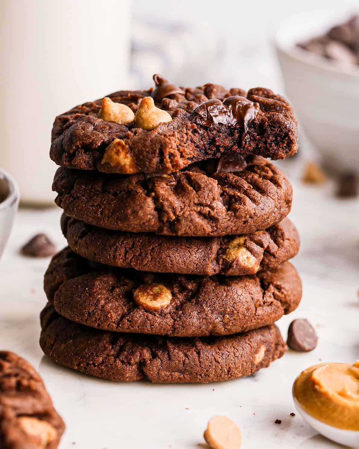 Stack of 5 chocolate peanut butter chip cookies with one cookie partially eaten on top.