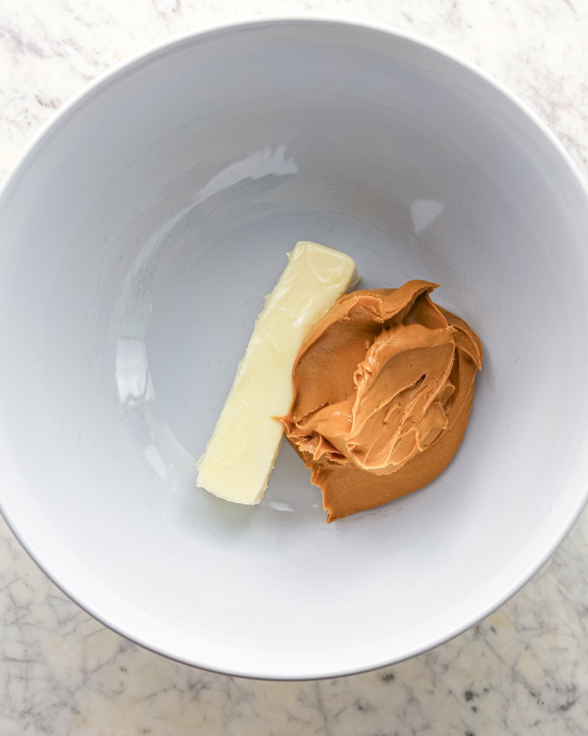 Making chocolate peanut butter chip cookies - butter and peanut butter placed in a white bowl.