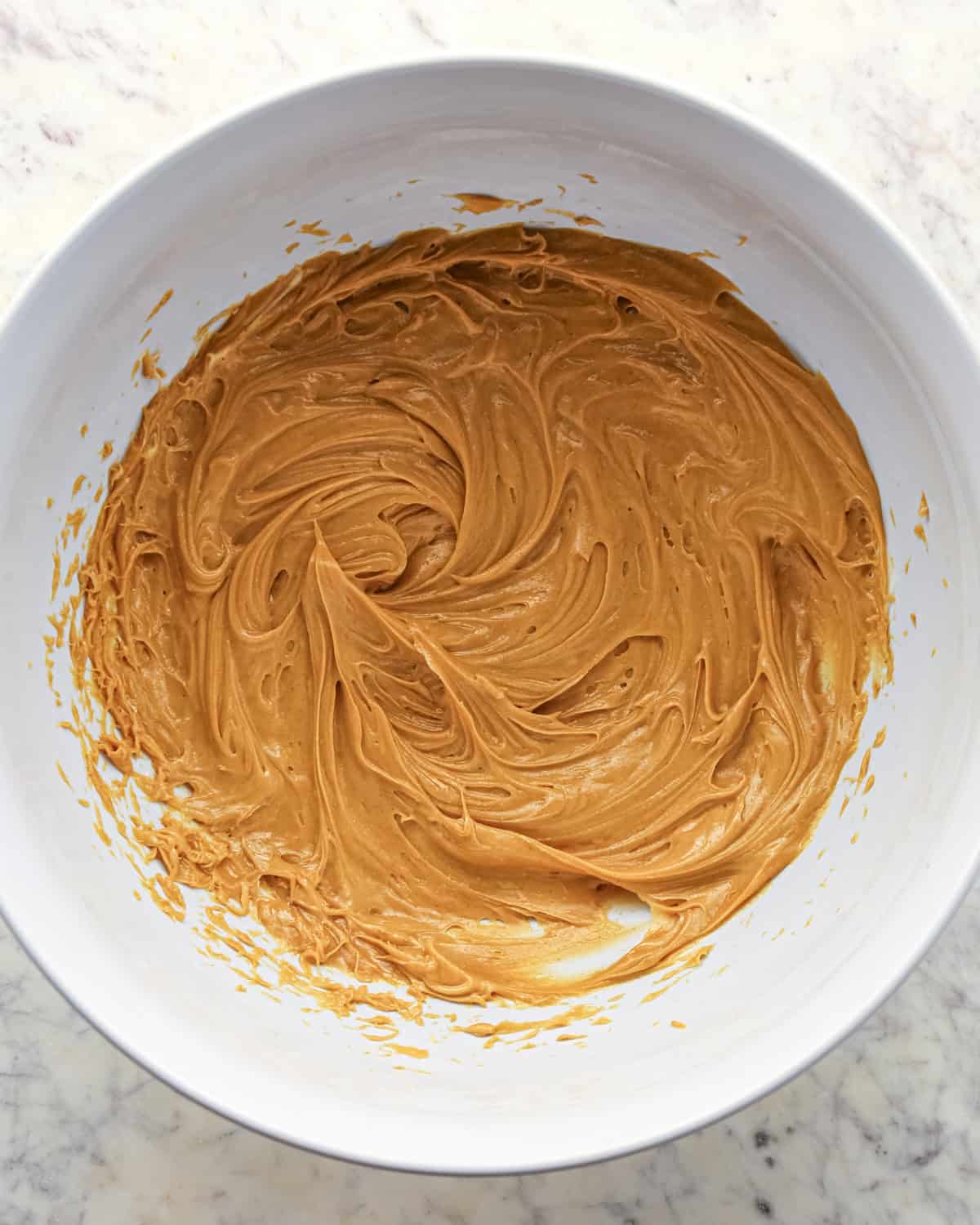 Making chocolate peanut butter chip cookies - butter and peanut butter placed in a white bowl and mixed together.