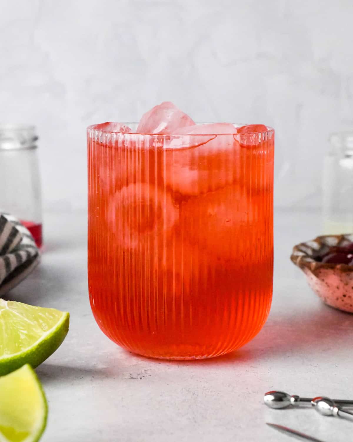 Making a Shirley Temple - close-up photo of grenadine, lime juice, and ginger ale in a clear glass with ice.
