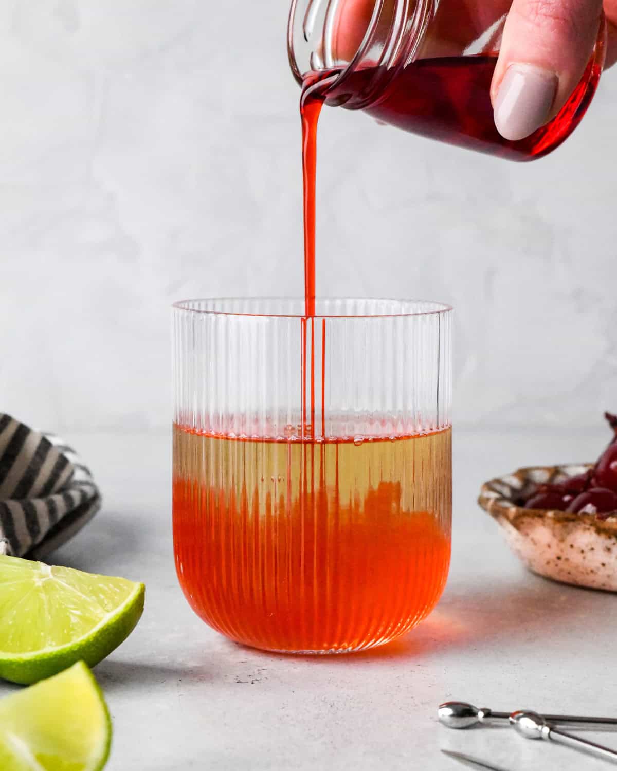 Making a Shirley Temple - close-up photo of grenadine being poured into a clear glass with ginger ale.
