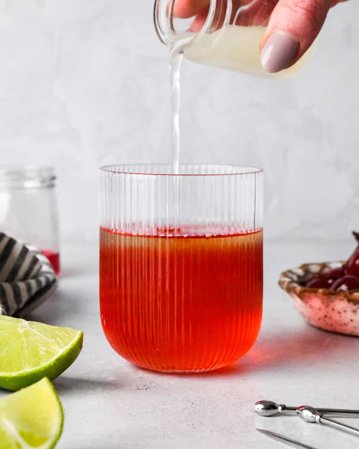 Making a Shirley Temple - close-up photo of lime juice being poured into a clear glass with ginger ale and grenadine.