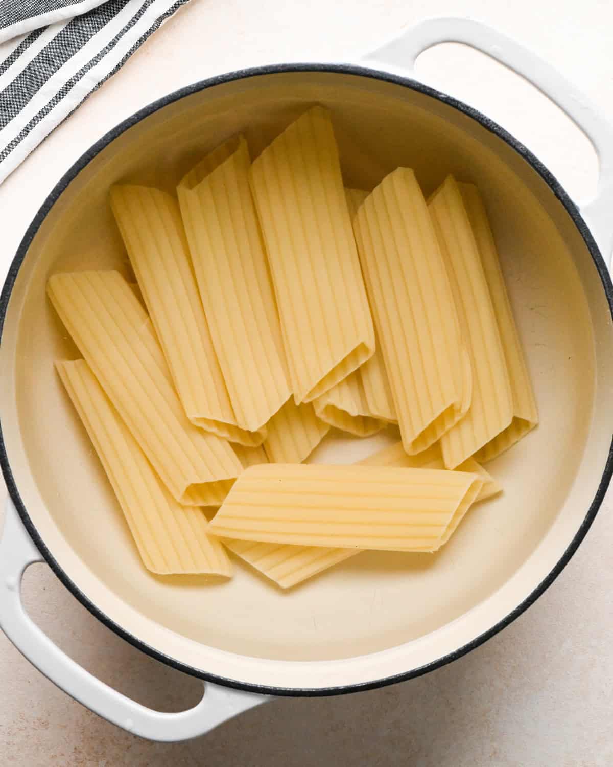 Making stuffed manicotti - overhead photo of manicotti noodles being cooked in a white pot.