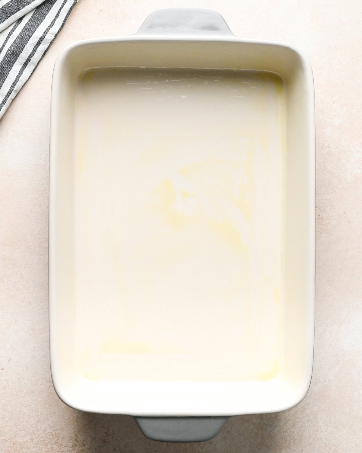 Overhead photo of a 9x13" white baking dish greased with oil and sitting on a countertop.