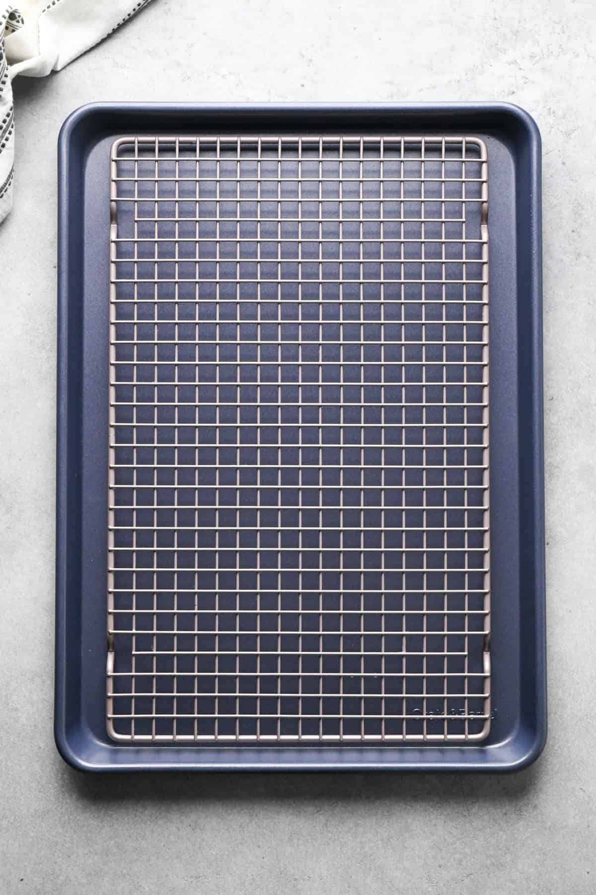 Making pizza chicken: overview photo of a silver cooling rack placed on top of a dark baking sheet.