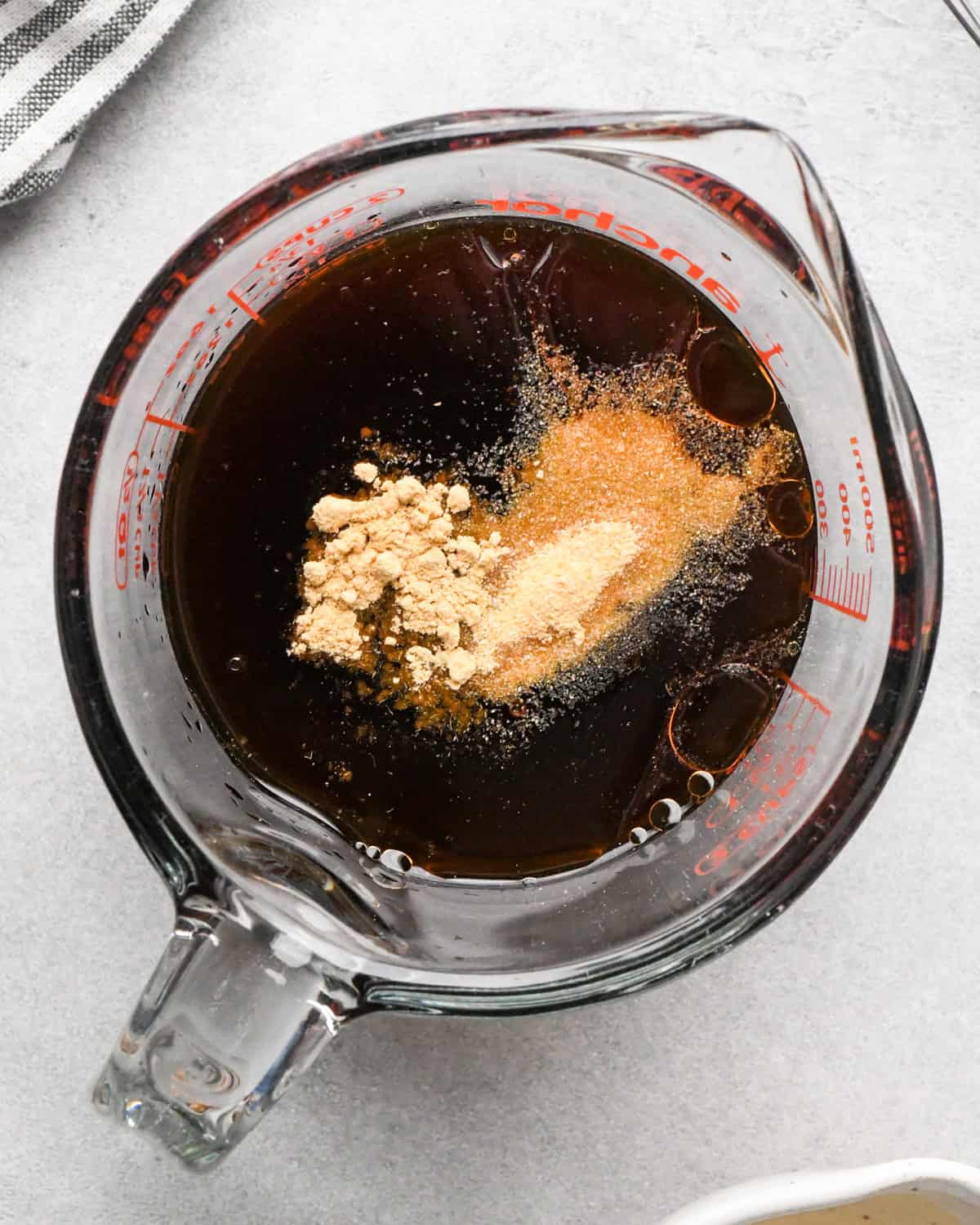 Making beef and broccoli: adding the ingredients for the sauce to a liquid measuring cup.