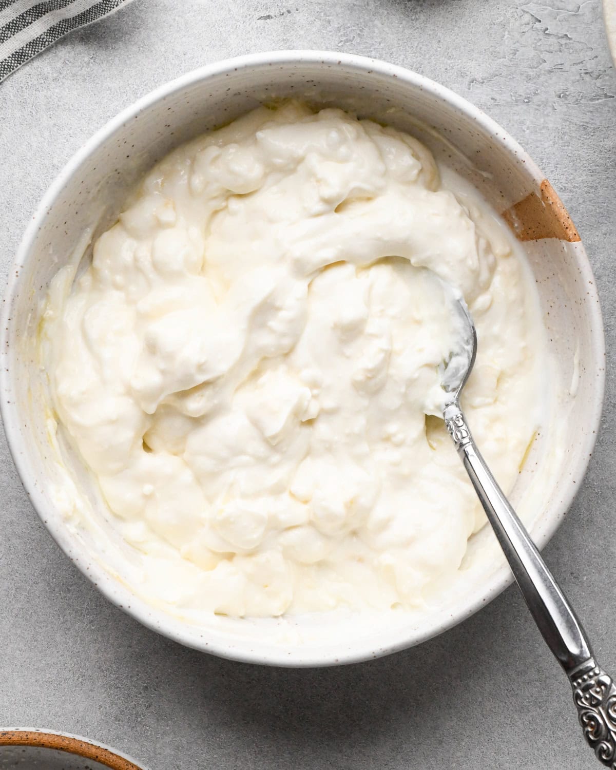 Making Greek chicken salad: beginning to mix the creamy dressing ingredients in a white speckled bowl.