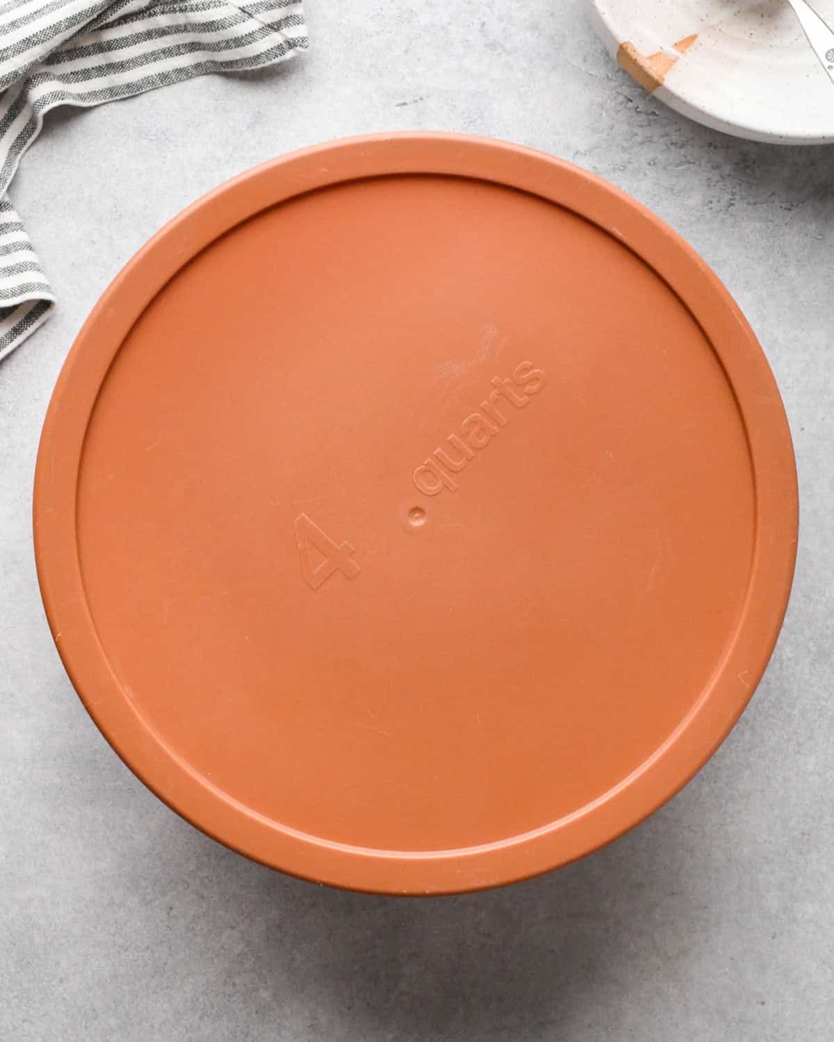 Making Greek chicken salad: completed salad is shown in a clear glass Tupperware dish and covered with an orange lid.