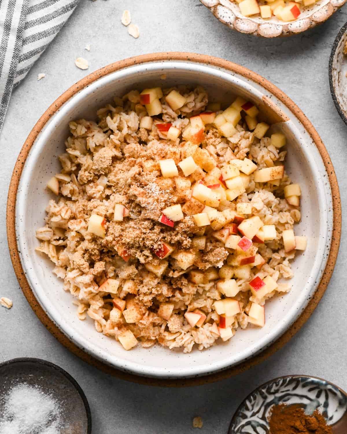 showing how to make oatmeal flavors, apples, brown sugar and cinnamon on top of cooked oatmeal in a bowl