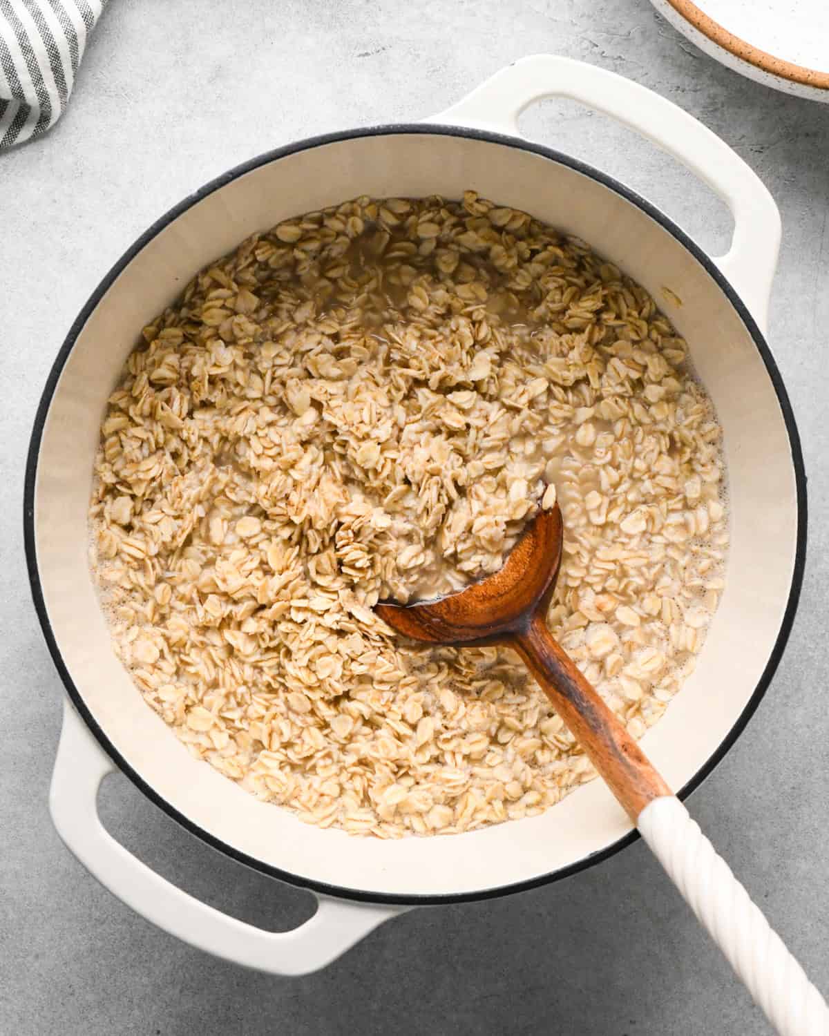 a wooden spoon stirring oatmeal and water in a pot showing how to make oatmeal