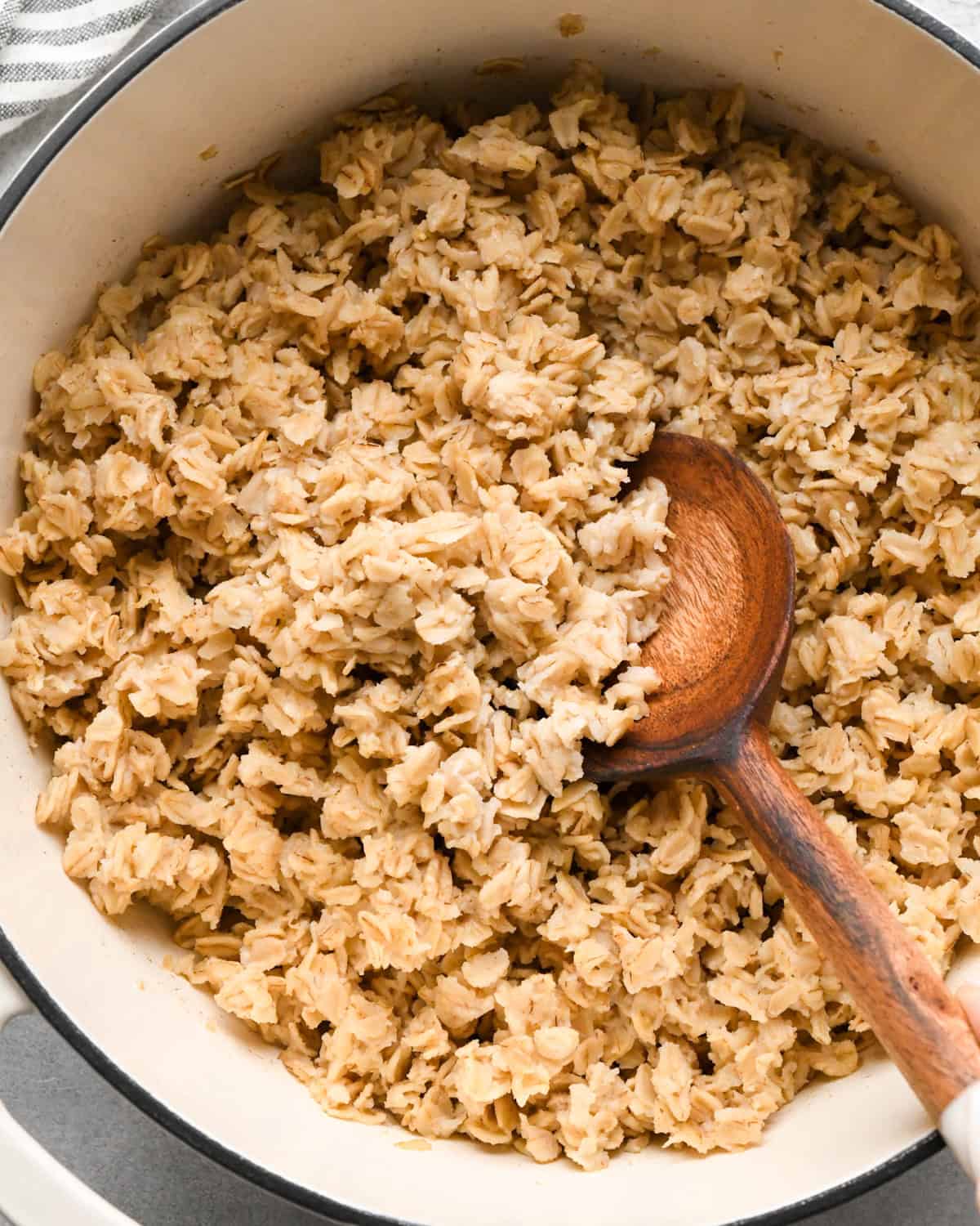 a wooden spoon stirring cooked oatmeal in a pot
