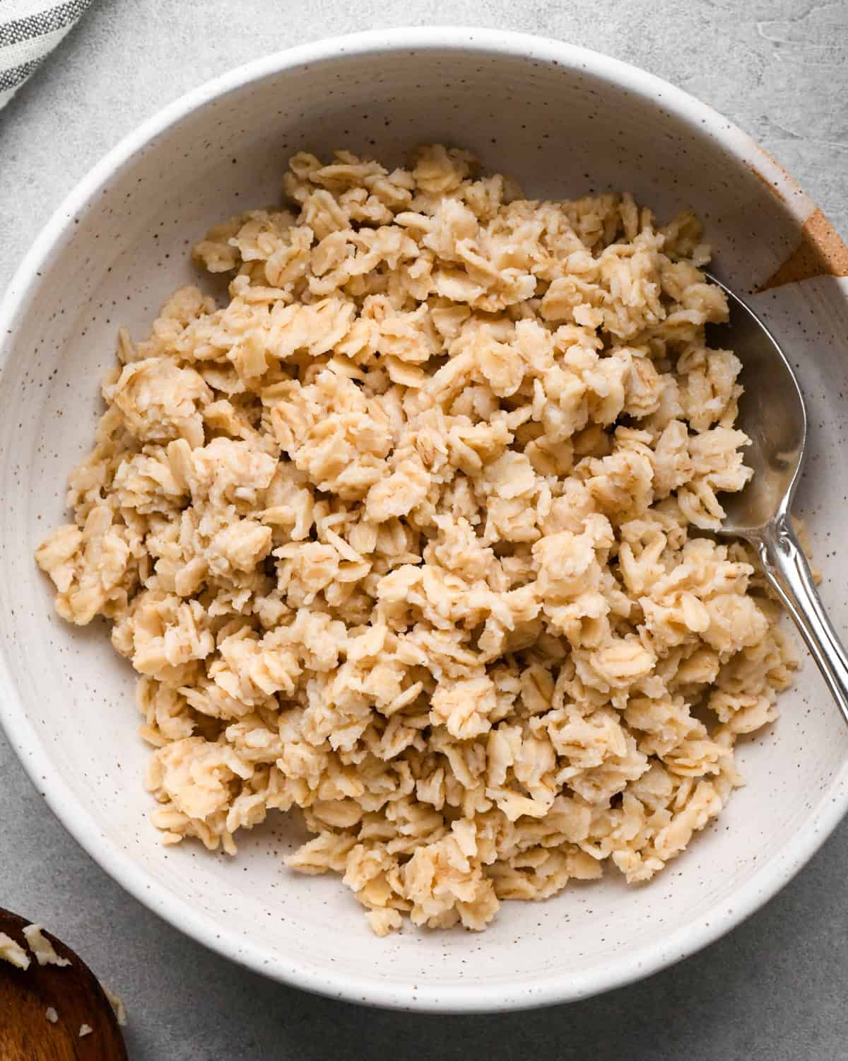 cooked oatmeal in a bowl with a silver spoon