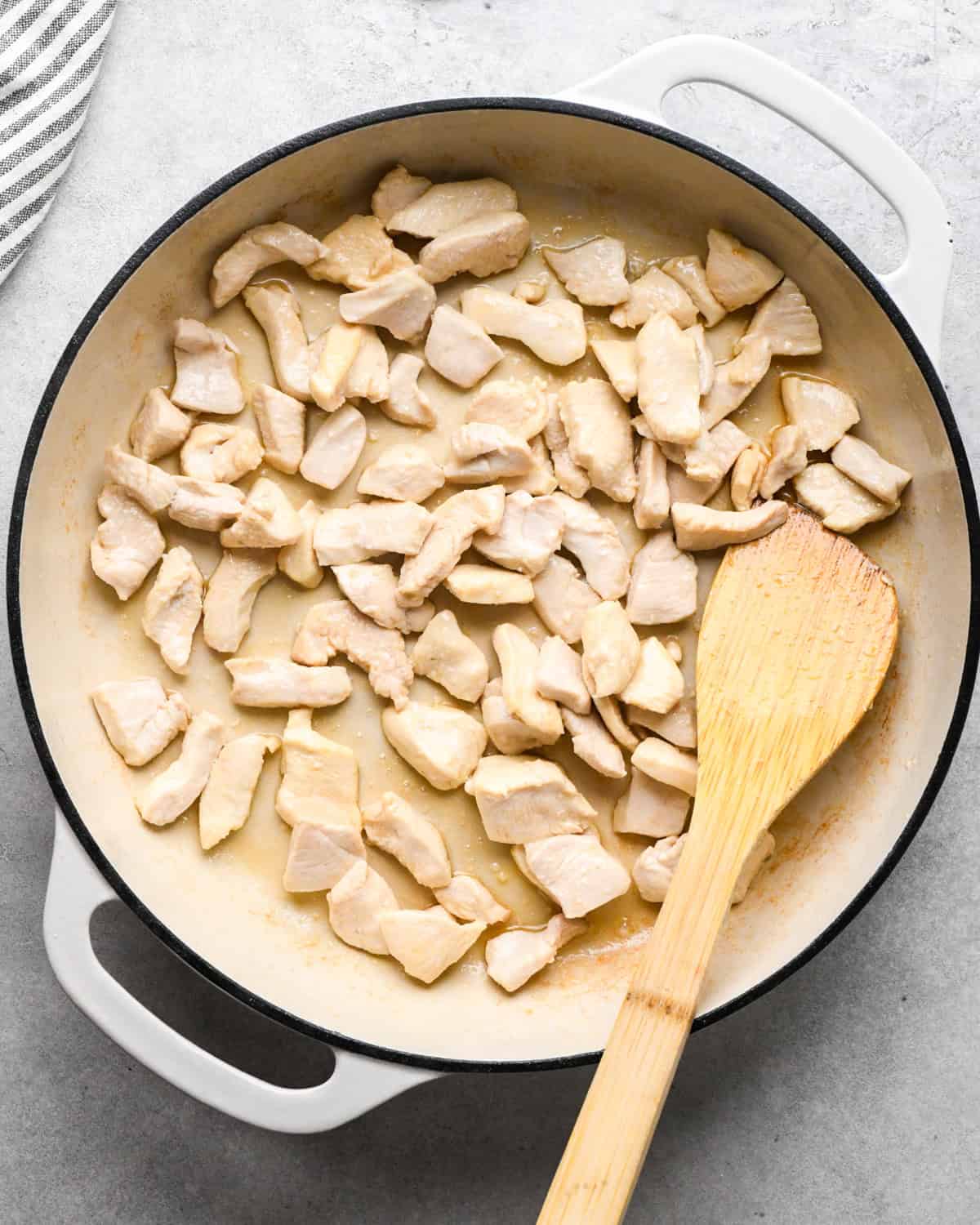 Making chicken fried rice: overhead photo of chicken being cooked in a white skillet.