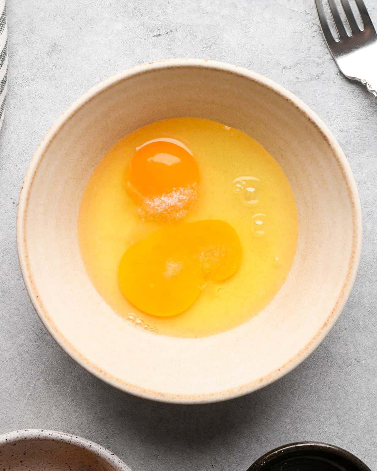 Making chicken fried rice: overhead photo of eggs cracked into a small white bowl.