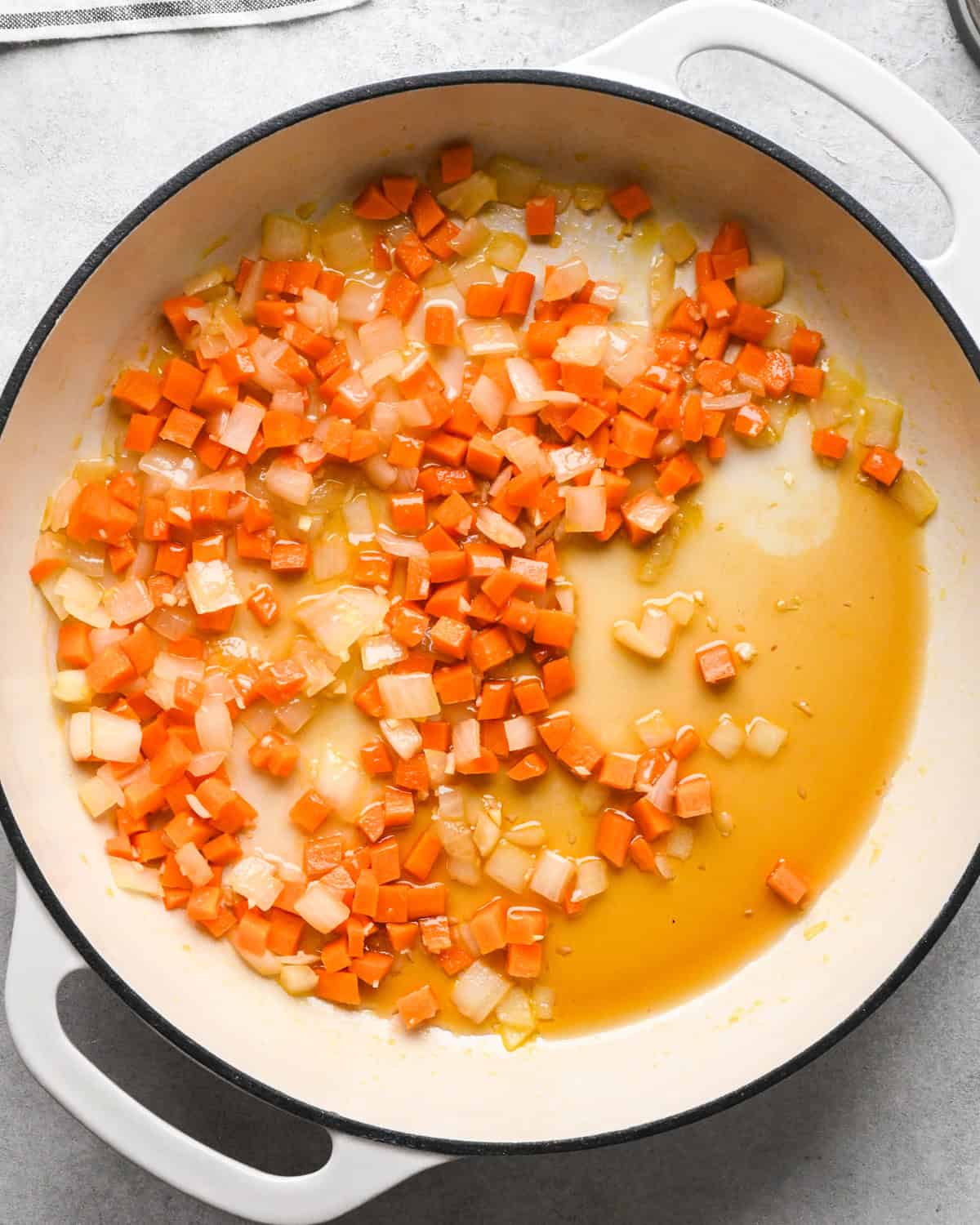 Making chicken fried rice: overhead photo of vegetables being sautéed in a white skillet.