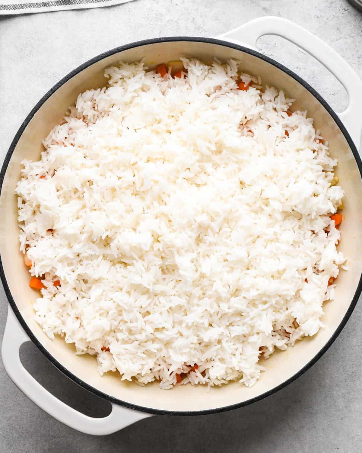 Making chicken fried rice: rice is added to the skillet with cooked vegetables.