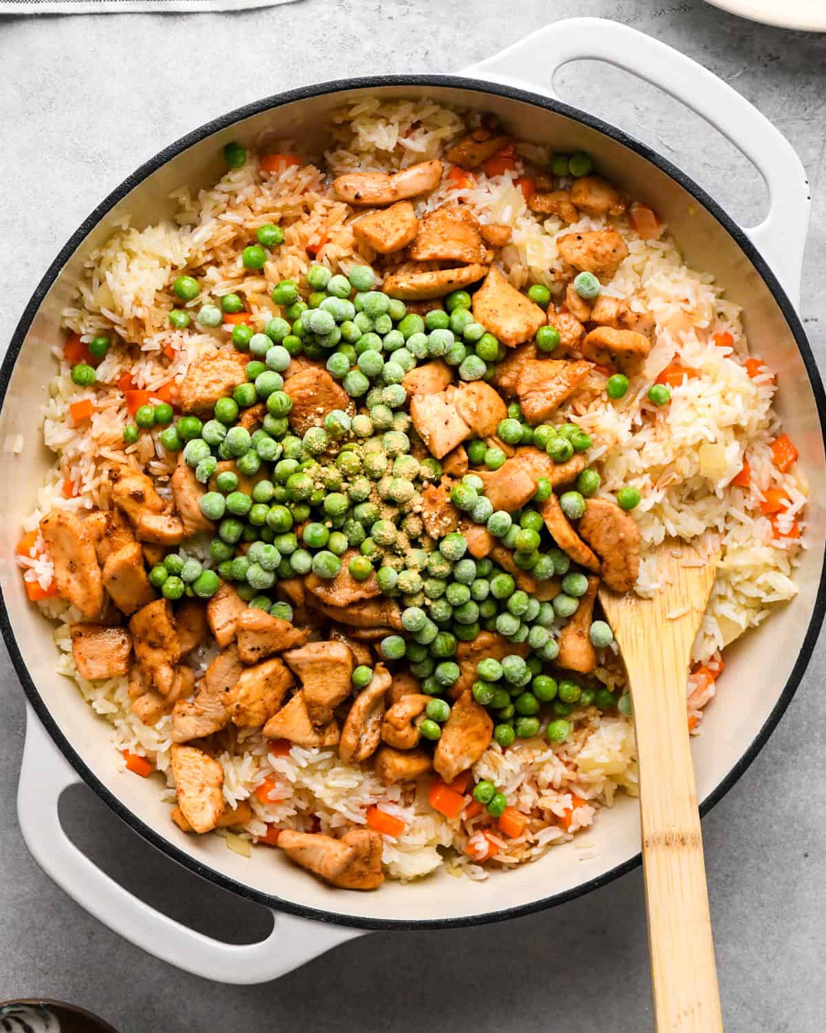 Making chicken fried rice: prepared chicken and peas are added to the skillet with rice and cooked vegetables.