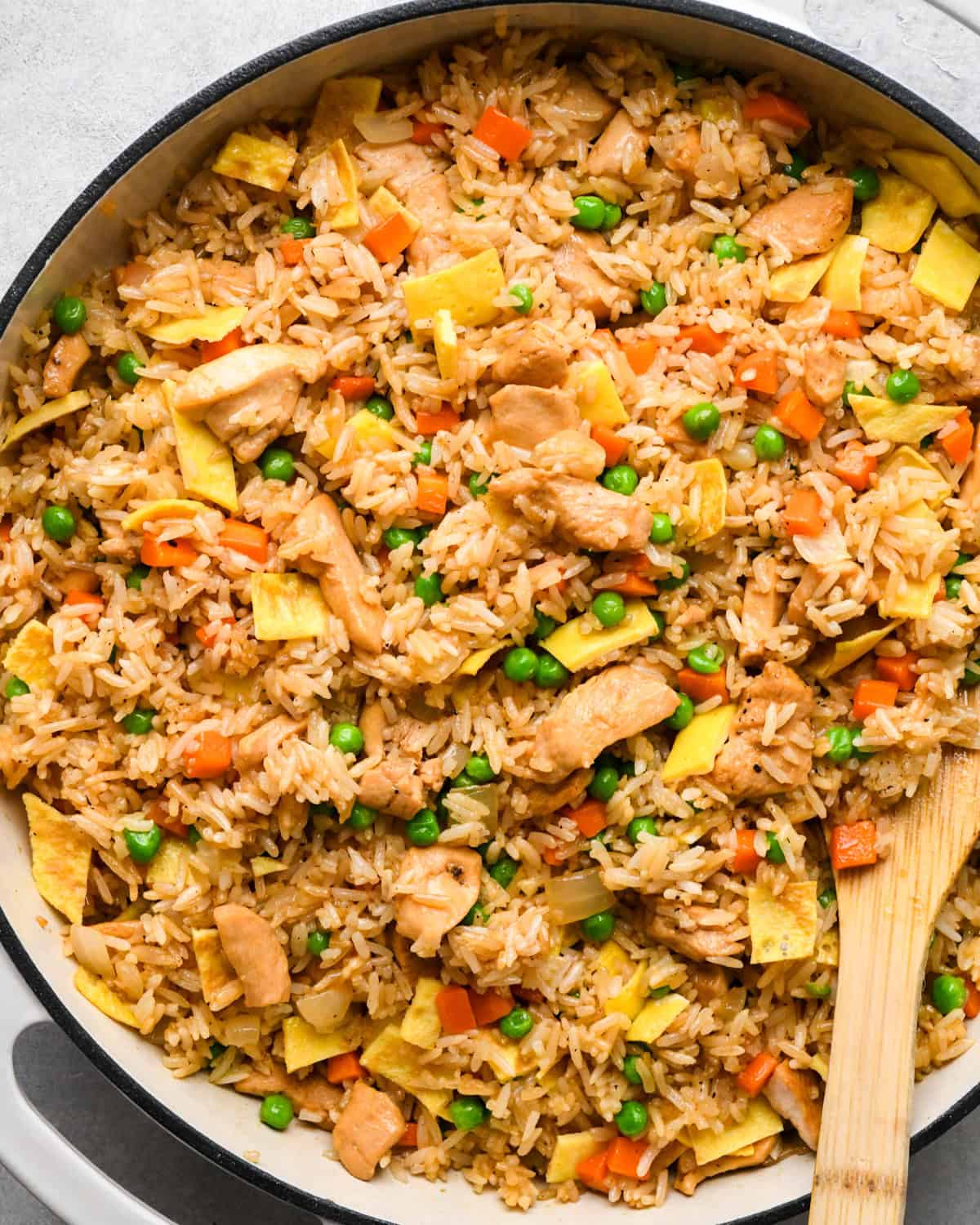 Making chicken fried rice: close-up photo of completed fried rice being stirred with a wooden spatula and ready to serve.