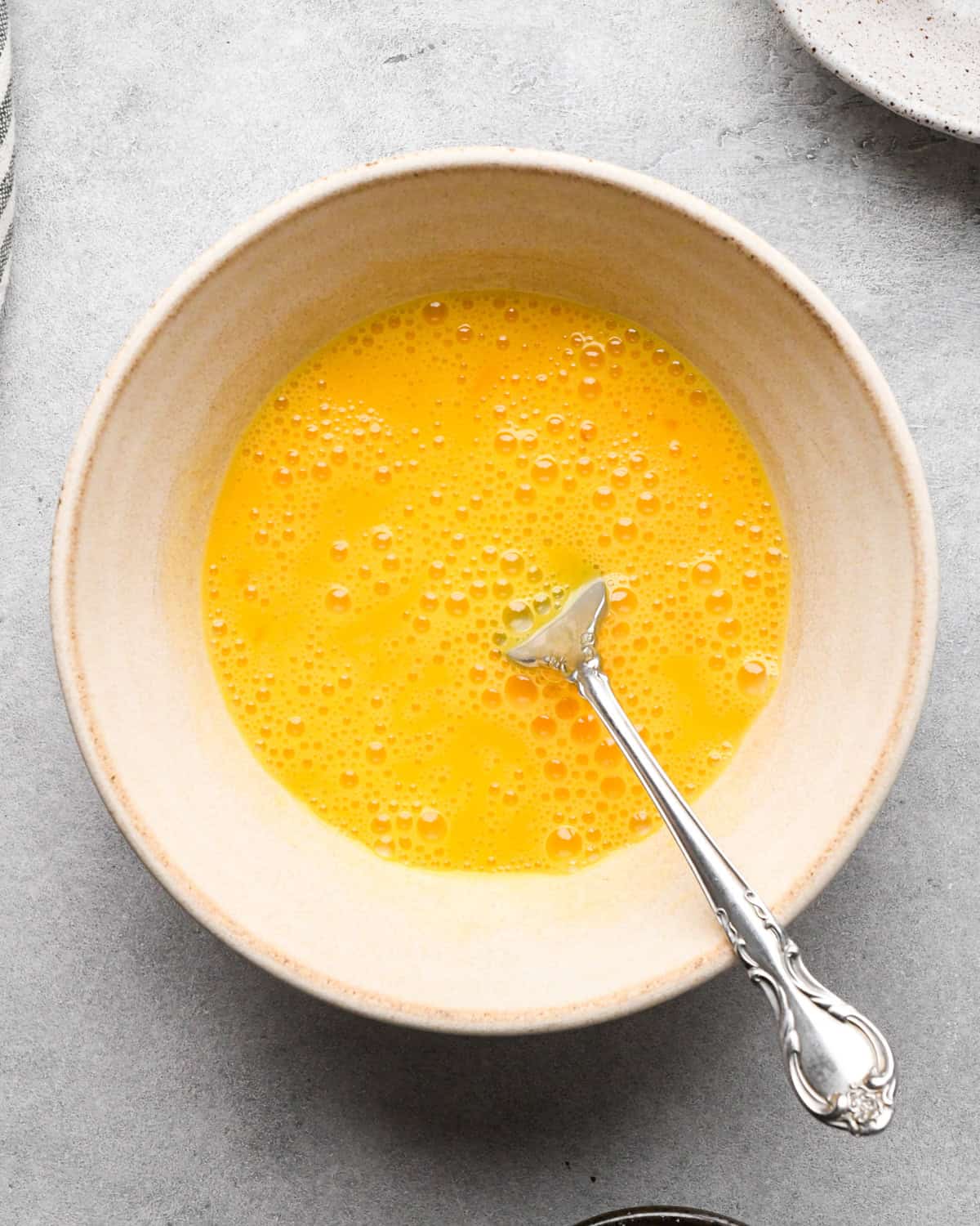 Making chicken fried rice: overhead photo of eggs cracked into a small white bowl and beaten with a fork.