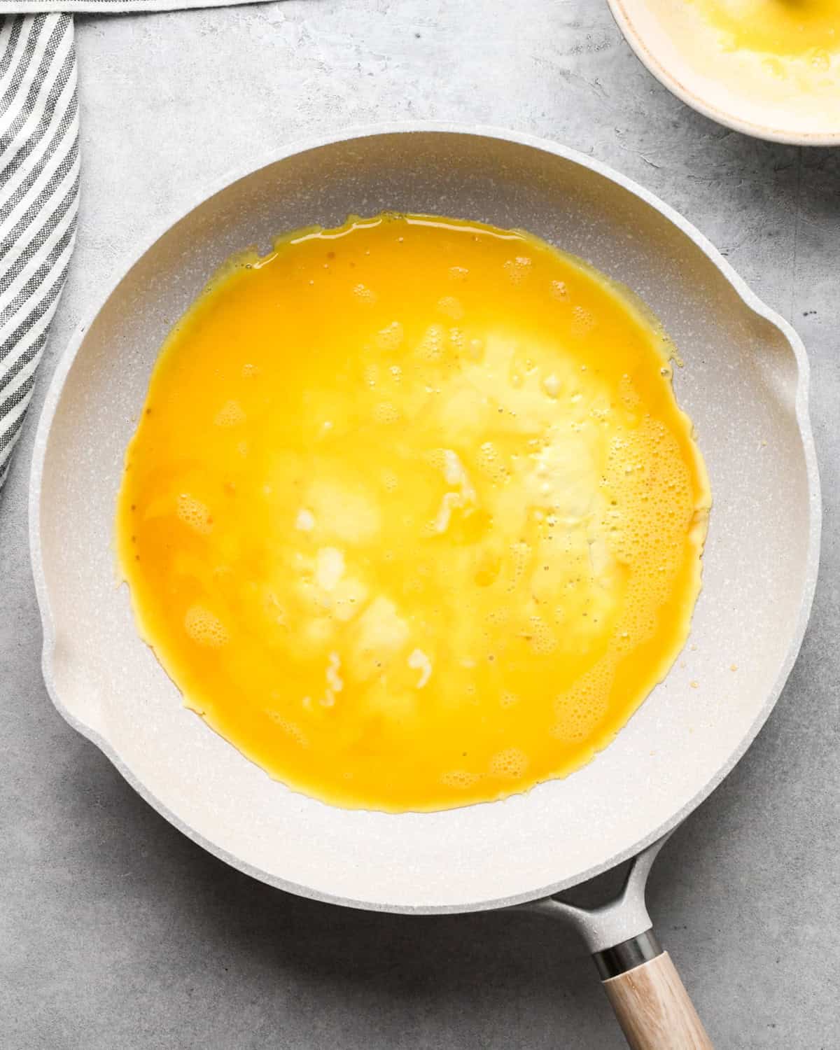Making chicken fried rice: overhead photo of eggs being cooked in a white skillet.