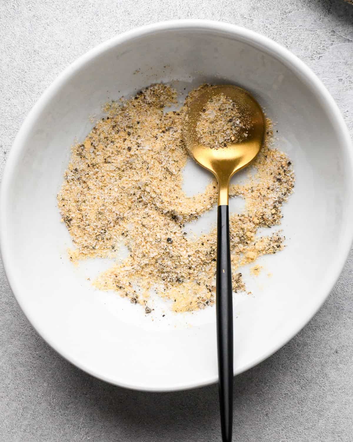 Making chicken fried rice: overhead photo of a small white bowl of spices being mixed together with a spoon.