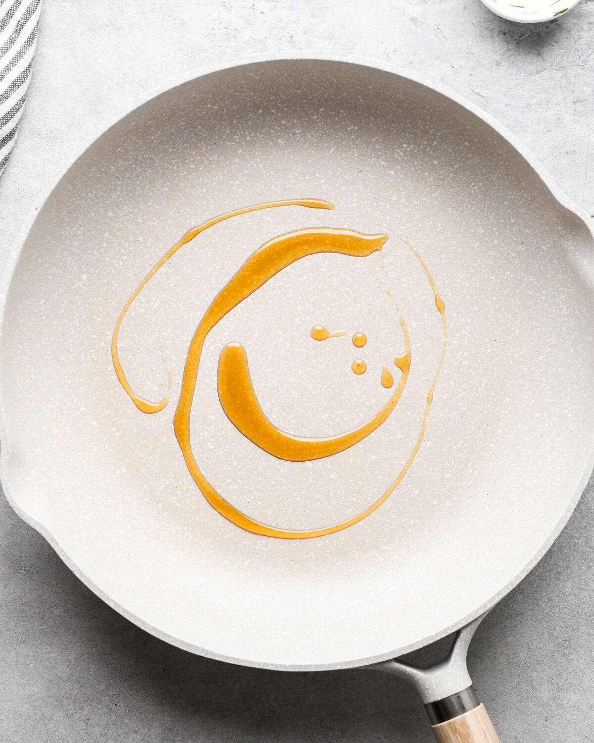 Making chicken fried rice: overhead photo of oil being heated in a white skillet.