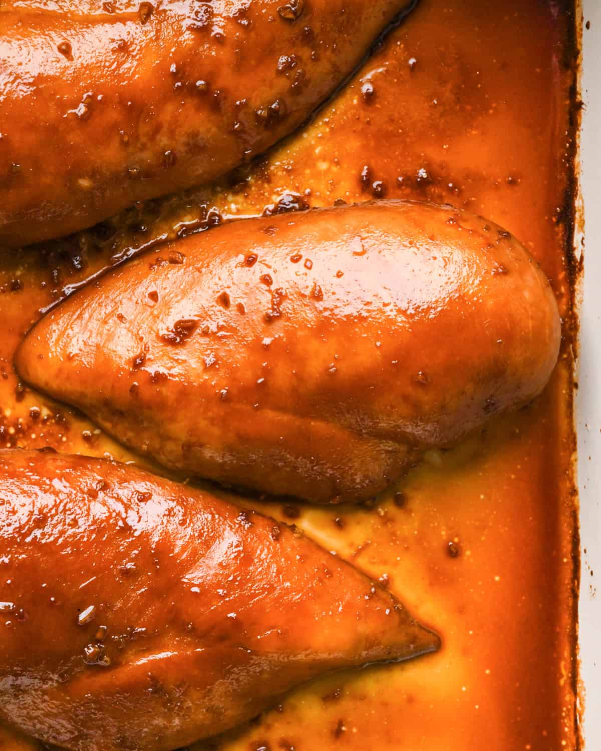 Making teriyaki chicken: close-up photo of marinated chicken breasts in a white casserole dish.