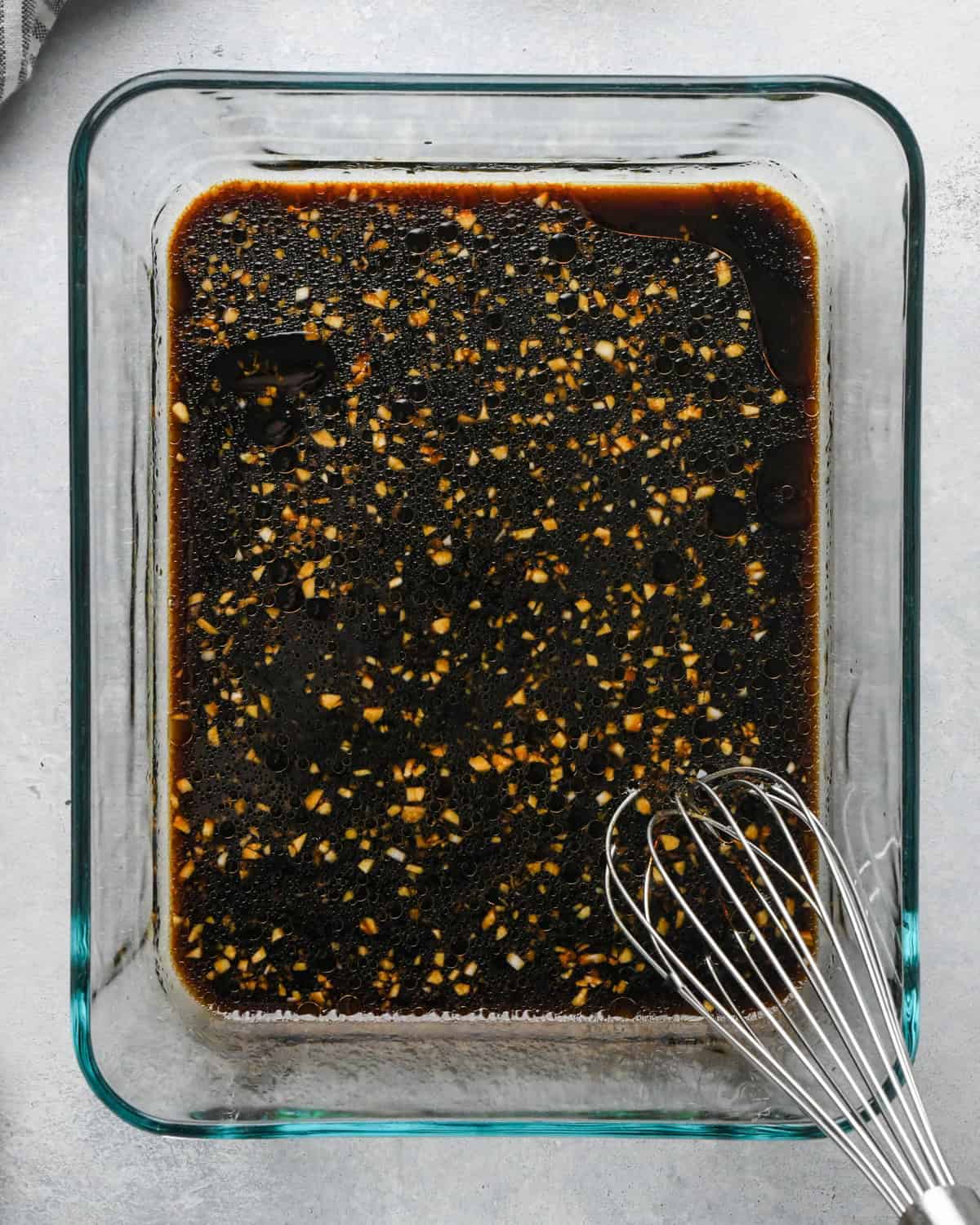 Making teriyaki chicken: overhead photo of teriyaki sauce ingredients in a clear rectangle Pyrex dish being whisked together.