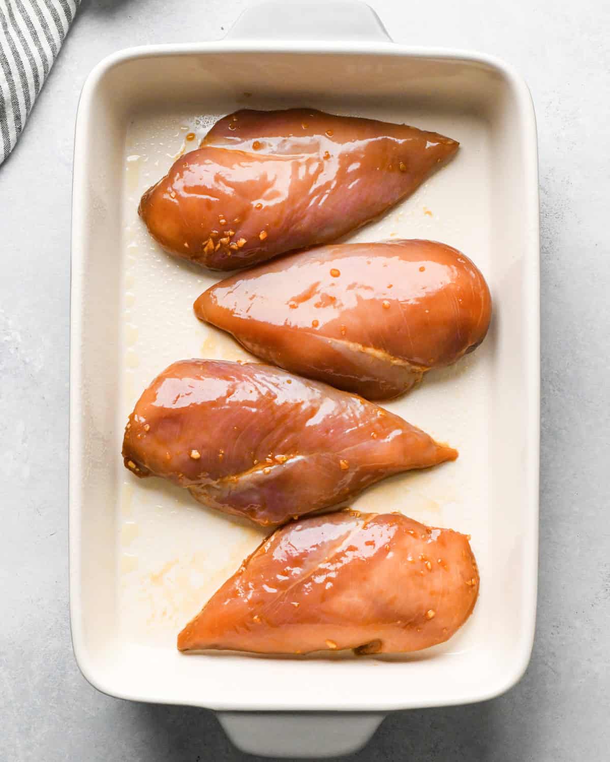 Making teriyaki chicken: marinated chicken breasts are placed in a white casserole dish.